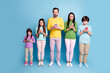 © deagreez - Multigenerational family standing together using smartphones against a blue background, parents and children focused on screens