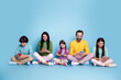 © deagreez - Family sitting together on blue background using smartphones and enjoying digital connection