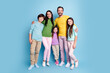 © deagreez - Happy family portrait of parents and three children standing together against a blue background, casual clothing and warm smiles showing togetherness, love, and modern family lifestyle