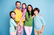 © deagreez - Happy family portrait of parents with three smiling children standing together against a blue background showing love, unity and family bonding