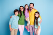 © deagreez - Happy family portrait of parents with three children smiling together against a blue background, casual clothing, parental embrace and sibling bond, warm lifestyle image