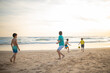 © KONSTANTIN SHISHKIN - Boys playing soccer on sandy beach at sunset