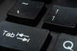 © Khalil - Close-up macro of black keyboard keys Tab and number 1 with white lettering, dramatic lighting on textured plastic surface. Technology concept.