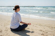 © Юлия Завалишина - Yoga calm mindfulness meditation. Young healthy woman practicing yoga on beach. Woman sitting in lotus pose meditating relaxing connection with nature by the sea. Girl doing breathing practice
