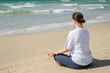 © Юлия Завалишина - Yoga calm mindfulness meditation. Young healthy woman practicing yoga on beach. Woman sitting in lotus pose meditating relaxing connection with nature by the sea. Girl doing breathing practice