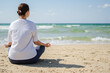 © Юлия Завалишина - Yoga calm mindfulness meditation. Young healthy woman practicing yoga on beach. Woman sitting in lotus pose meditating relaxing connection with nature by the sea. Girl doing breathing practice