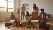© antuanetto - Happy group of diverse young friends packing cardboard boxes for college in a sunny living room for a moving to dorms concept and relocation preparation