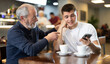 © JackF - Frustrated guy person scrolls down phone screen, indulges in sadness and memories. Elderly man comforts his son. Difficult period of life, everyday troubles
