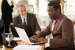 © JackF - African man sits at a table with employees in the office, they discuss investments and sales in companies. Employees working together in the office