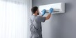 © Rifqi - HVAC technician wearing gloves inspecting wall-mounted air conditioner unit indoors, concept for home appliance repair, climate control maintenance and professional service advertising