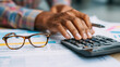 © Techno Stoks - close-up of hands using a calculator to create a financial plan on a desk with documents and glasses