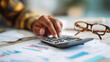 © Techno Stoks - close-up of hands using a calculator to create a financial plan on a desk with documents and glasses
