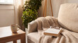 © Esther - Inviting and cozy living room corner featuring a comfortable sofa with a warm knitted blanket, a book, glasses.