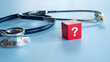 © MohamadFaizal - A red block with a white question mark standing next to a medical stethoscope on a blue background symbolizing medical uncertainty