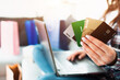 © Vlad - Online shopping concept. Close-up of credit cards. A woman buys things on the Internet on a laptop She must choose which credit card is more profitable.