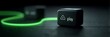 © Strother - Futuristic black cube device with glowing green neon play button and warning icon connected to fiber optic cable on dark textured surface for technology and gaming concepts