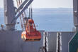© KONSTANTIN SHISHKIN - Cargo crane loads container at shipping port near water during sunny day