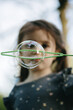 © Nataliya - Vertical portrait of a blurred girl playing with soap bubbles in a park.