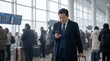 © Simone Matos - Businessman checking his phone while waiting in a busy airport terminal with luggage