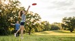 © MT - Young Caucasian Woman Throwing Red Frisbee in Sunny Park with Friend