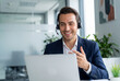 © Meow Creations - Smiling call center agent with a headset working on a laptop in a modern office