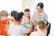© chokniti - Back to school and education concept of diverse schoolchildren study globe with teacher in bright classroom
