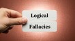 © Lily - Logical Fallacies text on white cards held by hand, critical thinking and philosophy concept, cognitive bias and reasoning errors