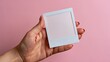 © Sawyer0 - Close-up of a woman's hand displaying an empty white photograph card over a bright magenta surface.