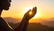 © Yasing - A silhouetted figure reaches towards a vibrant sunset, hands outstretched as if embracing the warmth and light of the fading day over a mountainous landscape.