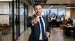© CREATIVE KNIT DESIGN - Confident businessman in a suit pointing his finger towards the camera while standing in a modern corporate office hallway during a workday to show leadership and professional recruitment