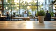 © Aleksandra - potted green plant on wooden table in a bright cozy coworking cafe with large glass windows, hanging lights and blurred people working on laptops conveying a calm focused atmosphere