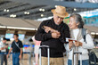 © Verin - active asian senior couple standing in airport terminal, looking at a ticket and checking time for self check-in on smartphone, elderly with modern lifestyle travel and airline journey