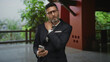 © Krakenimages.com - Man in suit holding smartphone and rubbing neck in hotel building while checking messages; discomfort workday.