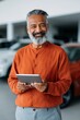 © Andrii Zastrozhnov - Elderly man standing while holding tablet inside dealership