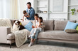© New Africa - Happy family and their dog on sofa at home