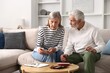 © New Africa - Pension and money savings. Senior couple counting their family budget at table on sofa indoors
