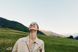 © SHOTPRIME STUDIO - A young woman in a beige jacket tilts her head back and smiles in a sunlit meadow under a clear sky, capturing a moment of lighthearted outdoor freedom and contentment.