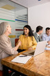 © fizkes - Diverse businesswomen shake hands during corporate meeting in conference room, concluding agreement, confirming partnership. Professional collaboration, respect, trust and teamwork in business concept