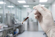 © Meow Creations - Hand in white medical glove holding pipette with dark liquid