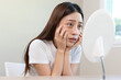 © Pormezz - Sleepless Asian woman looking her face in the mirror and worry about dark circles under eyes