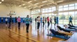 © UnPhouvith - A group of young people participate in a fitness class inside a gymnasium.