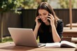 © miss irine - Woman talks on two phones while working on laptop outdoors. She smiles, multitasking with her devices and book. Freelancer managing work on sunny day.