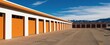 © miss irine - Self storage units with bright orange doors. White building facade has multiple garage style doors. Wide paved outdoor area leads to rows of rental spaces.