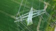 © maho - Aerial View of High Voltage Power Line Tower Over Green Agricultural Fields