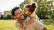 © ArtFocus Studio - Happy father and little daughter sharing a tender moment together in a sunny park with the girl giving her dad a piggyback ride and a sweet kiss on the cheek