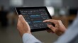 © Thares2020 - Hands hold a tablet displaying intricate digital data visualizations representing financial analysis and modern corporate monitoring