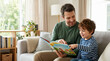 © Xenia - Happy father and son reading a picture book together on the couch. Smiling dad and child pointing at a storybook in a bright living room. Family bonding and early education concept