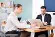 © JackF - Man and woman working in office, manager writes on paper or fills out contract forms, using laptop in work. Regional representative office company, carsharing, hiring staff.