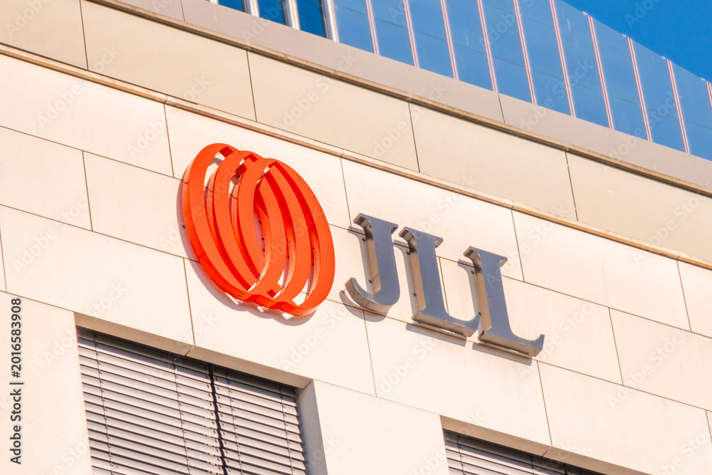JLL logo orange spiral symbol, building facade, blue sky background ...