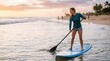 © velikiyzayats - Happy young woman paddleboarding on blue surfboard at sunset beach
